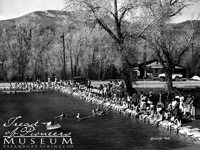 Large crowd of people sitting on the edge of the warm springs at Old Town Hot Springs in 1935.