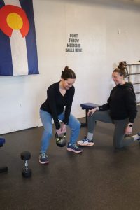 female personal trainer helping client with a kettle bell squat