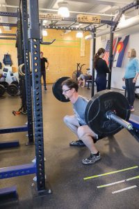 personal trainer demonstrating a back squat in with the squat bar